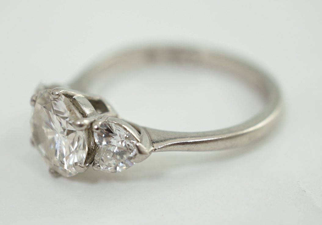 A modern platinum and single stone diamond ring, with two stone heart shaped diamond set shoulders